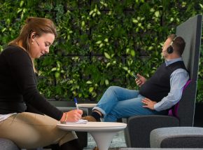workers sitting next to a vegetated wall.