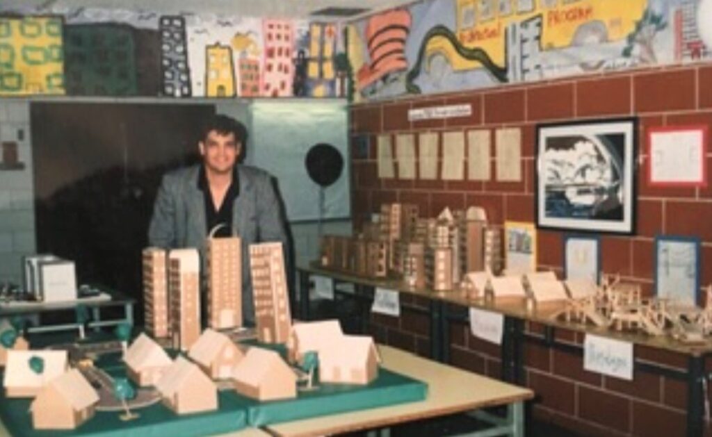 The author featured next to the STEM model projects. Various miniature buildings surround him.