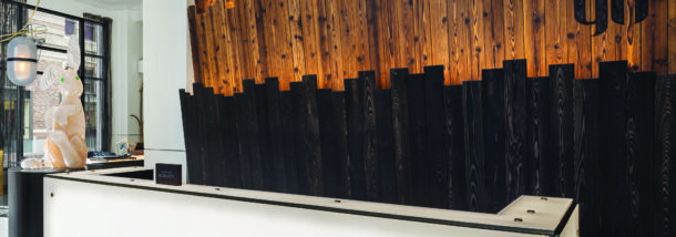white reception desk in the foreground with a multi-colored wood wall and a glass sculpture of a rabbit in the background.